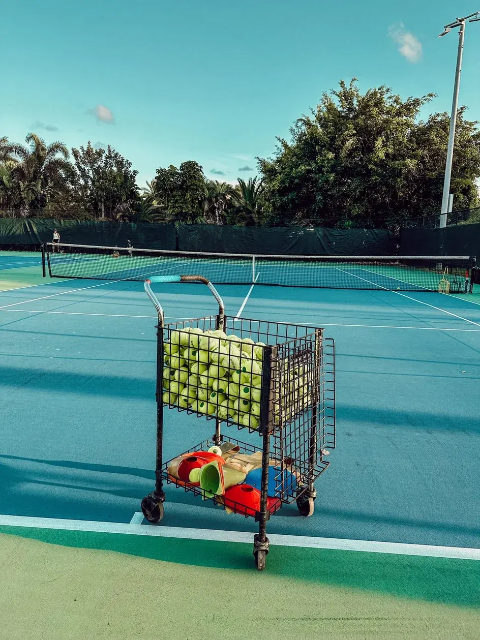 A cart of balls on court, set up for a coaching session