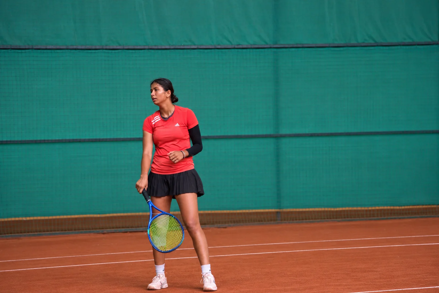 A player waiting to receive on a clay court, racquet down